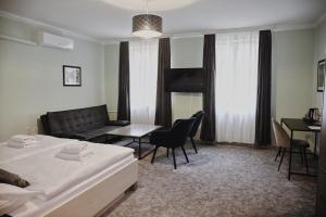 a bedroom with a bed and a couch and a table at Penzion Kastiel in Veľký Krtíš