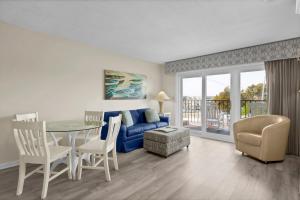a living room with a blue couch and a table and chairs at Summer Sands - 104 by Sea Scape Properties in Wrightsville Beach +10 photos