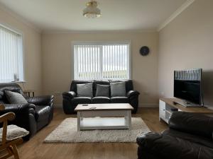 a living room with a couch and a tv at Leagarth House in Baltasound