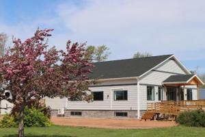 a white house with a porch and a tree at EcoSun Hostel in Montague