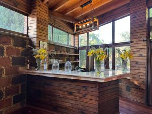 a bar in a room with windows and flowers in vases at Hotel Matea San Isidro in Tonatico