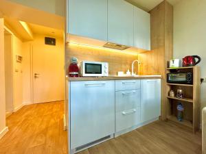 a kitchen with white cabinets and a microwave at SPA Apartment Alex in Borovets