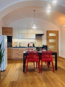 a kitchen with a black table and red chairs at Apartmán CORA in Jaroměř