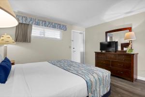 a bedroom with a bed and a dresser with a mirror at Summer Sands - 304 by Sea Scape Properties in Wrightsville Beach +9 photos