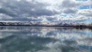 a reflection of snow covered mountains in a body of water at Sevan lake view in Tsovagyugh