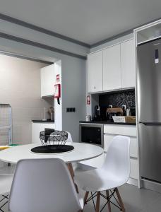 a kitchen with a white table and white chairs at Harmonia Guest House in Ponta Delgada