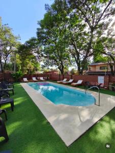 a swimming pool with a green lawn and trees at Terra Iguazú Suites in Puerto Iguazú