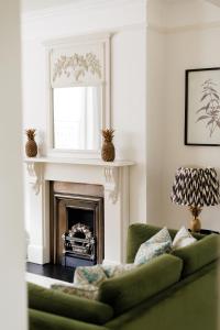 a living room with a green couch and a fireplace at Stylish, Spacious, Oxford Townhouse, Driveway parking in Oxford