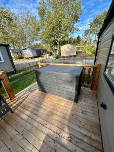 a wooden deck with a bench on the side of a house at Chalet Jersey in Lauwersoog