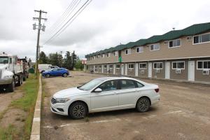 a white car parked in a parking lot next to a building at Plains Motor Inn in Stettler