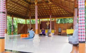 two people sitting on the floor of a pavilion at The Dukuh Retreat in Tabanan