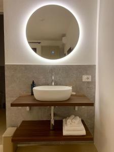 a bathroom with a sink and a round mirror at Residenza Marrone in Montefalco +86 photos