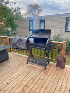 a grill on a wooden deck with a house at Chalet Jersey in Lauwersoog
