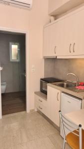 a kitchen with white cabinets and a sink and a bathroom at Prokymaia Apartment 1 in Rethymno +15 photos