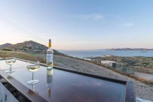 a bottle of wine sitting on a table with two wine glasses at Dust in The Wind Sunrise in Triovasálos +3 photos