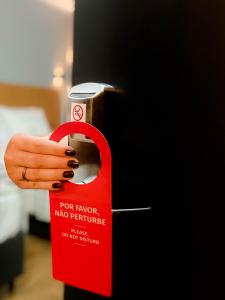 a person holding a red door key with a cup on it at INN TERRAÇO Hotel in Mirandópolis