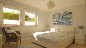 a bedroom with a bed and a chair and two windows at Haus Jonas in Tinnum
