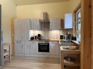 a large kitchen with white cabinets and a sink at Ferienhaus 4 Elemente in Selchow mit tollem Garten in Selchow