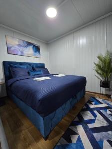 a bedroom with a blue bed and a potted plant at Moderna smeštaj Kula in Kula