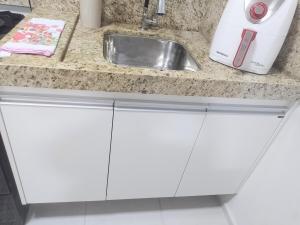 a kitchen counter with white cabinets and a sink at Juhh Bella Condomínio in Botucatu +28 photos