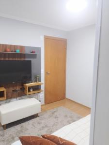 a living room with a television and a door at Juhh Bella Condomínio in Botucatu
