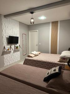 a bedroom with two beds and a flat screen tv at Pousada Luar in Chapada dos Guimarães