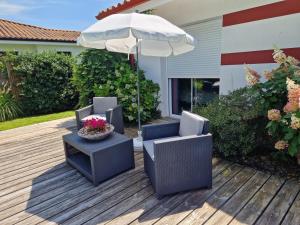 a patio with two chairs and an umbrella at Villa Nelson Classée 3 étoiles in Moliets-et-Maa