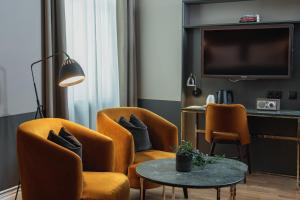 a living room with two chairs and a table and a tv at Home Hotel Temperance in Malmö