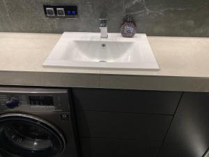 a white sink in a bathroom with a washing machine at CentralPark in Kostrzyn nad Odrą +29 photos