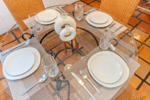 a glass table with white plates and silverware on it at Casa Hidalgo Hideaway in Chapala