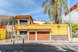 a yellow building with orange doors on a street at Casa Hidalgo Hideaway in Chapala