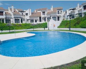 a large pool with blue water in front of houses at La Escapada in El Ronquillo