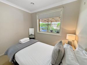 a bedroom with a white bed and a window at Glens Haven with Lakeviews and Outdoor Firepit in Wagga Wagga