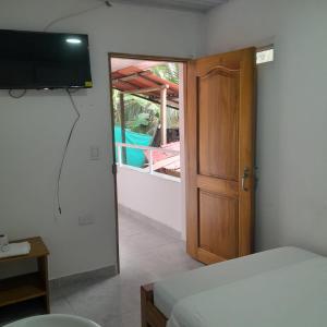 a room with a bed and a television and a door at Villa del coco Hospedajes in Arboletes