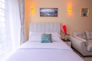 a bedroom with a white bed and a couch at charming Naivasha studio apartment in Naivasha