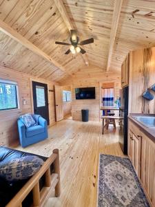 a log cabin living room with a ceiling fan at Oceanfront Sunset View Cabin in Milbridge