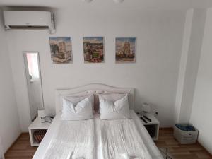 a bedroom with a white bed with four pictures on the wall at SWEET APT Zenica in Zenica