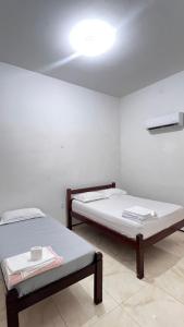 two beds in a room with a light on the ceiling at CAMA & CAFÉ BED & BREAKFAST HOSPEDARIA MORRO BRANCO 3 MIN A PÉ DAS FALÉSIAs 2 QUADRAS DA PRAIA 1 QUADRA DO MIRANTE & FEIRINHA in Beberibe