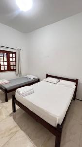 two beds in a room with a window at CAMA & CAFÉ BED & BREAKFAST HOSPEDARIA MORRO BRANCO 3 MIN A PÉ DAS FALÉSIAs 2 QUADRAS DA PRAIA 1 QUADRA DO MIRANTE & FEIRINHA in Beberibe
