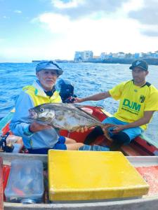 two men sitting on a boat with a fish at Artimar- B&Breakfast in Ponta do Sol