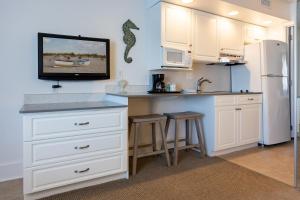 a kitchen with white cabinets and a counter with a refrigerator at Concord Suites in Avalon