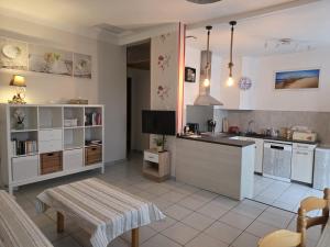 a kitchen with white cabinets and a table and a tv at La Grillotte in Vieux-Boucau-les-Bains +22 photos