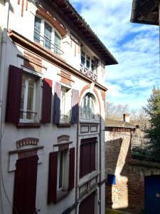 a white building with red doors and windows at La Cachette Urbaine in Albi
