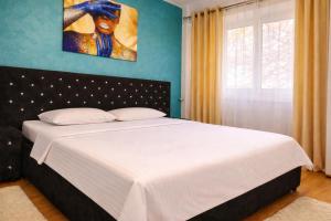 a bedroom with a white bed with a blue wall at Justin Ultra-Central Apartment in Galaţi