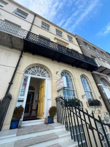 a building with a yellow door and stairs in front at The Edenhurst Guesthouse in Weymouth