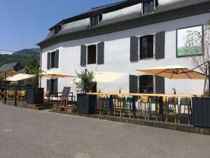a restaurant with tables and umbrellas in front of a building at Maison Lavillete - Chambres d'hôtes en Vallée d'Ossau in Bielle