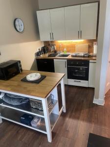 a kitchen with white cabinets and a wooden counter top at An Cuilidh in Port Bannatyne