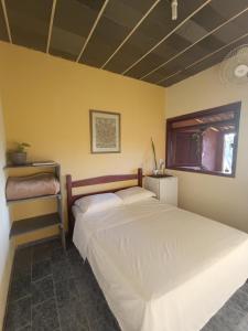 a bedroom with a bed and a yellow wall at Chalés Vale Encantado - Serra do Cipó in Jaboticatubas