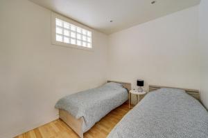 two beds in a white room with a window at Les LILAS in Les Lilas