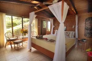 a bedroom with a bed with a canopy at Coconut Grove Beachfront Cottages in Matei